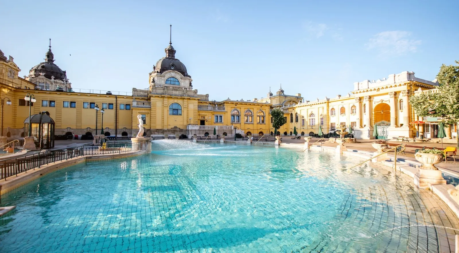 Széchenyi Thermal Bath's main outdoor pool in morning sun, with the domed yellow neo-baroque palace behind it