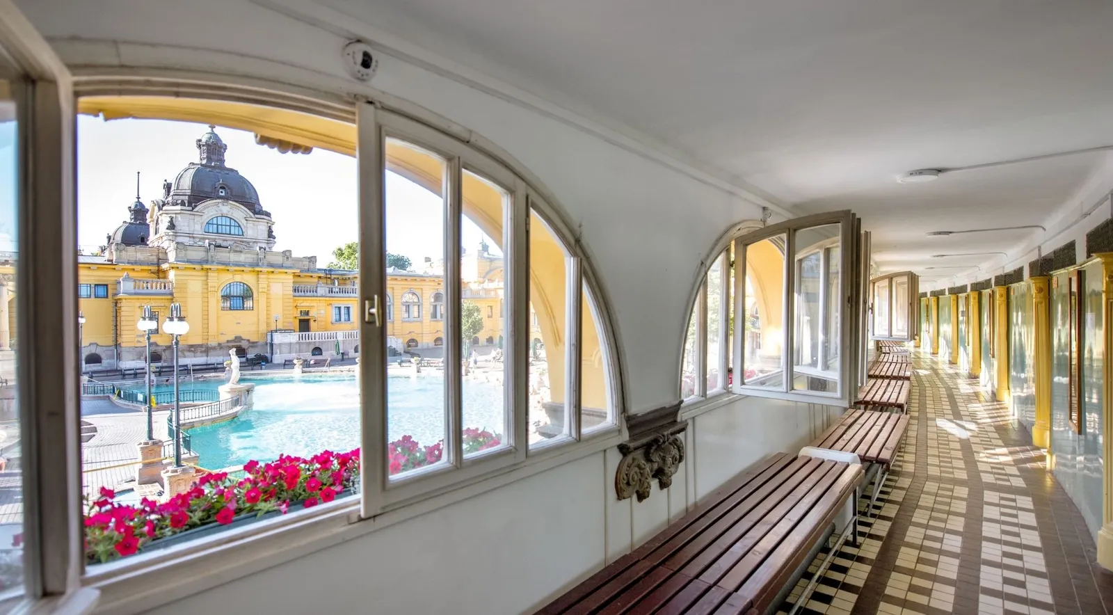 Looking through the arched windows of a Széchenyi corridor onto the outdoor pool and the domed wing