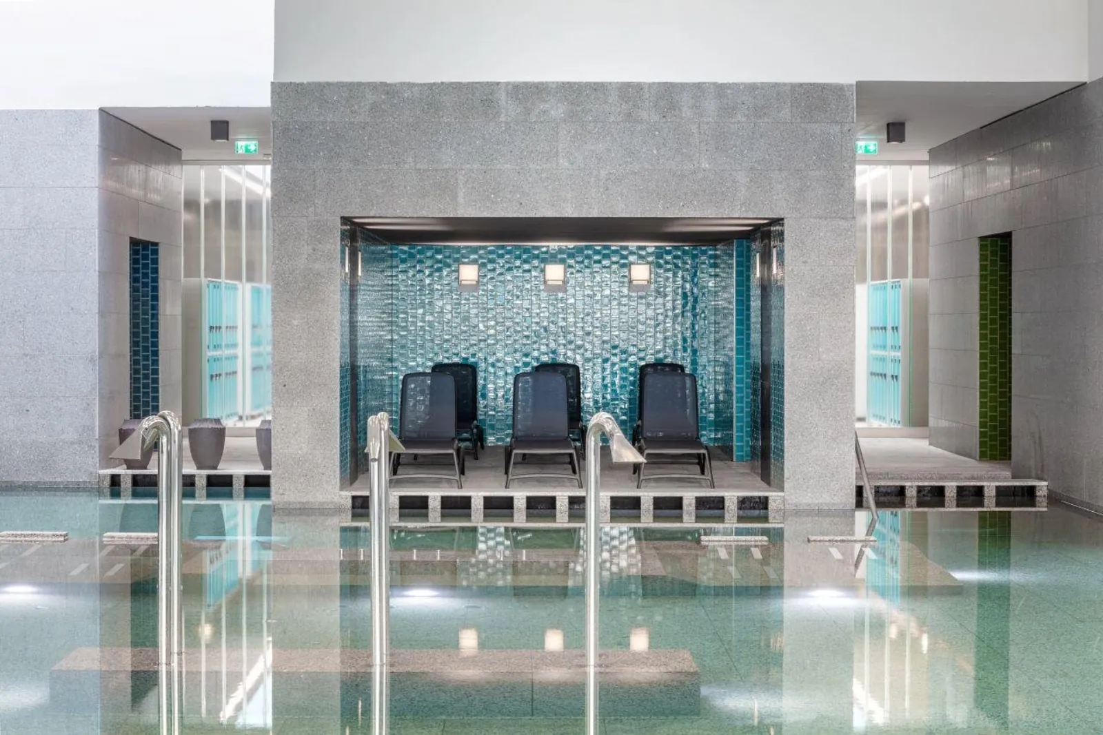 Indoor pool at Pesterzsébet with loungers in a blue-tiled alcove of grey stone
