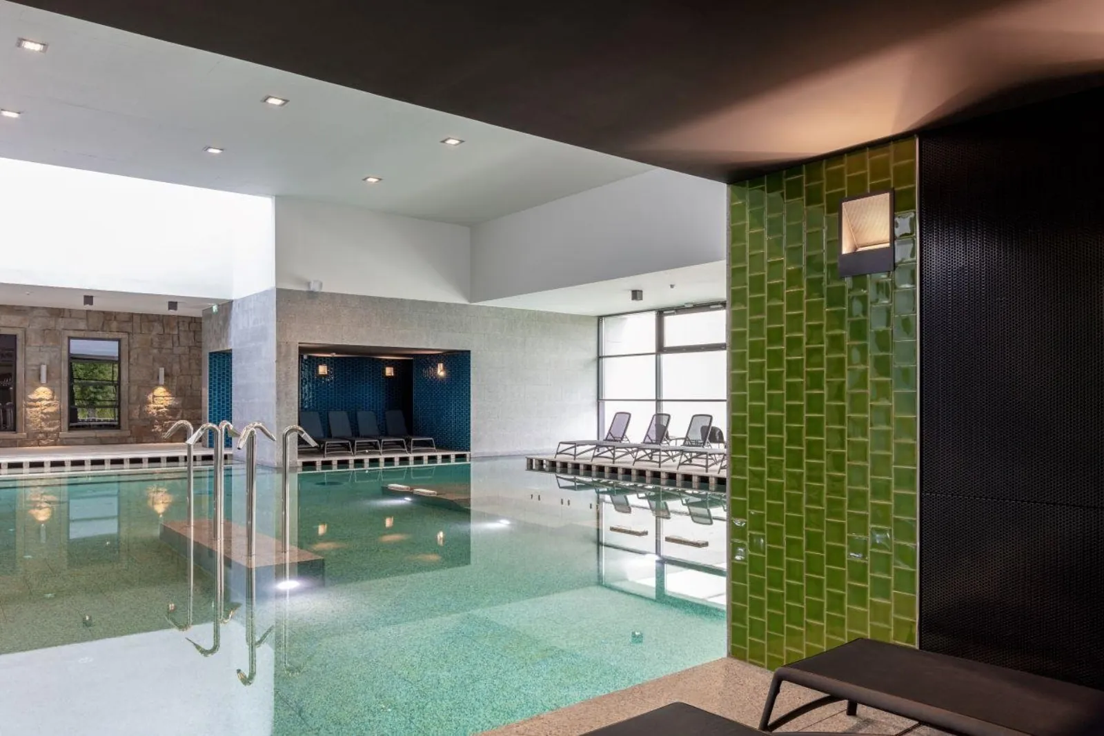 Indoor thermal pool hall at Pesterzsébet with green tiles and loungers by the windows