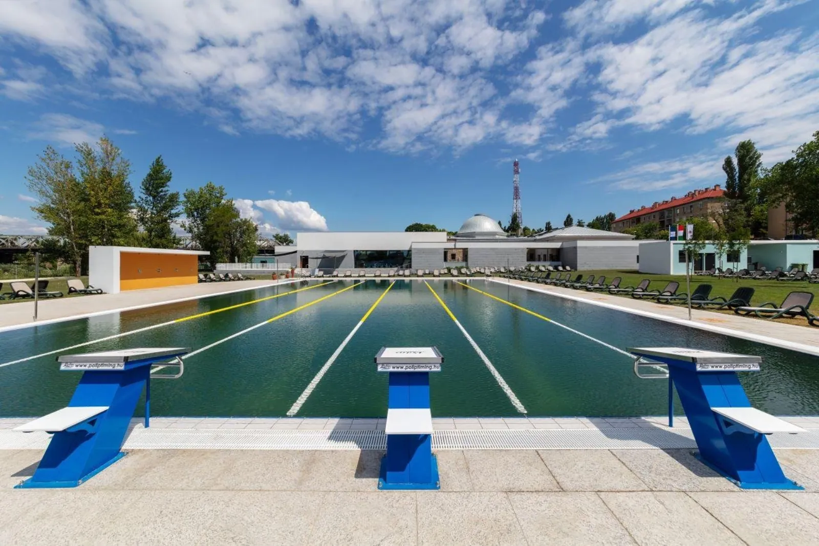 Outdoor lane swimming pool at Pesterzsébet with blue starting blocks and the domed building