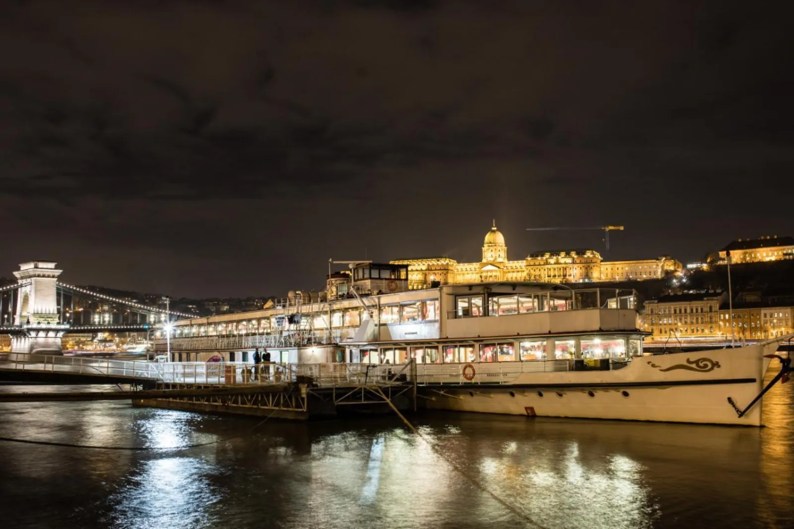 Historic Danube cruise ship moored at night with Chain Bridge and Buda Castle lit up