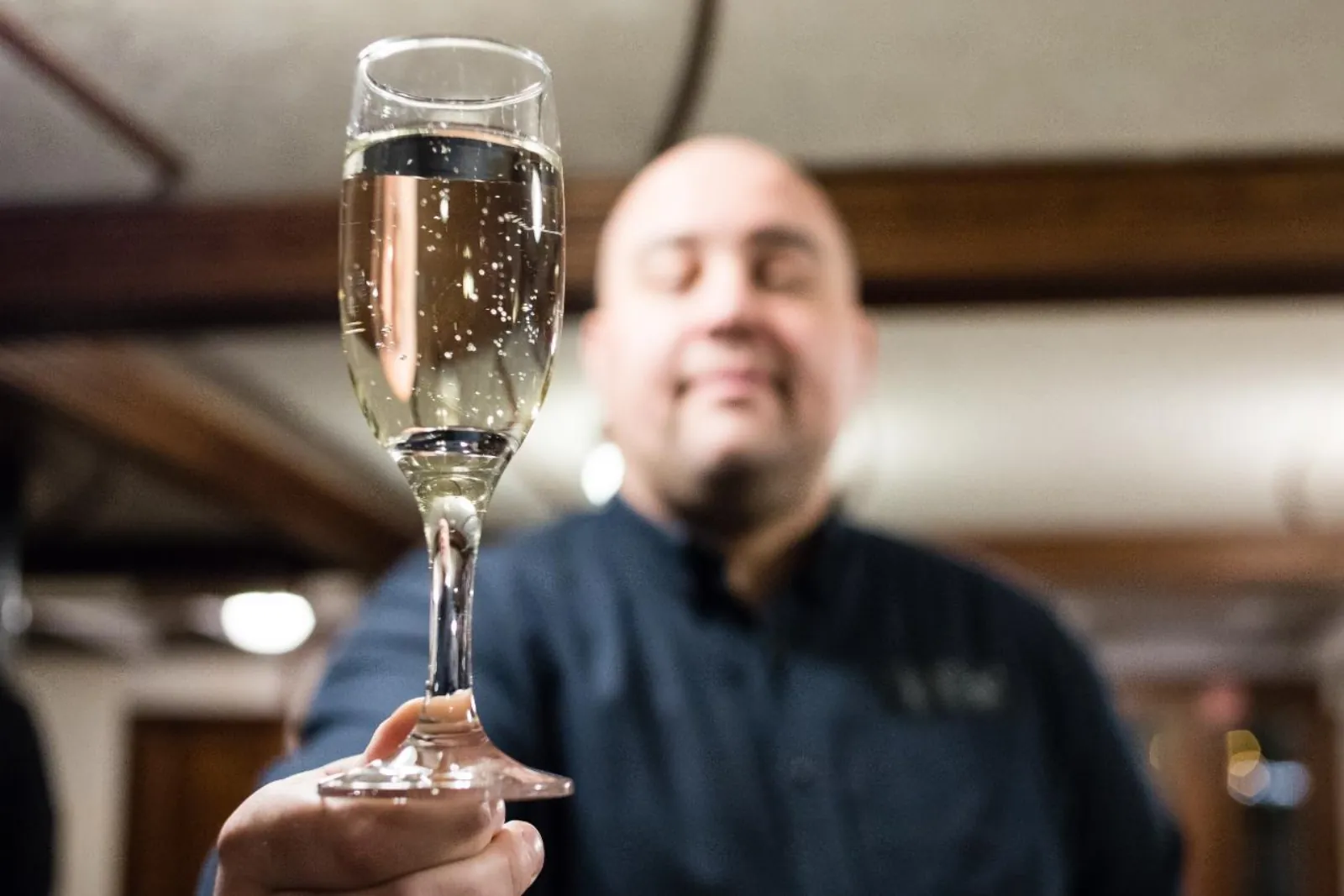 Crew member raising a glass of sparkling wine inside the cruise ship