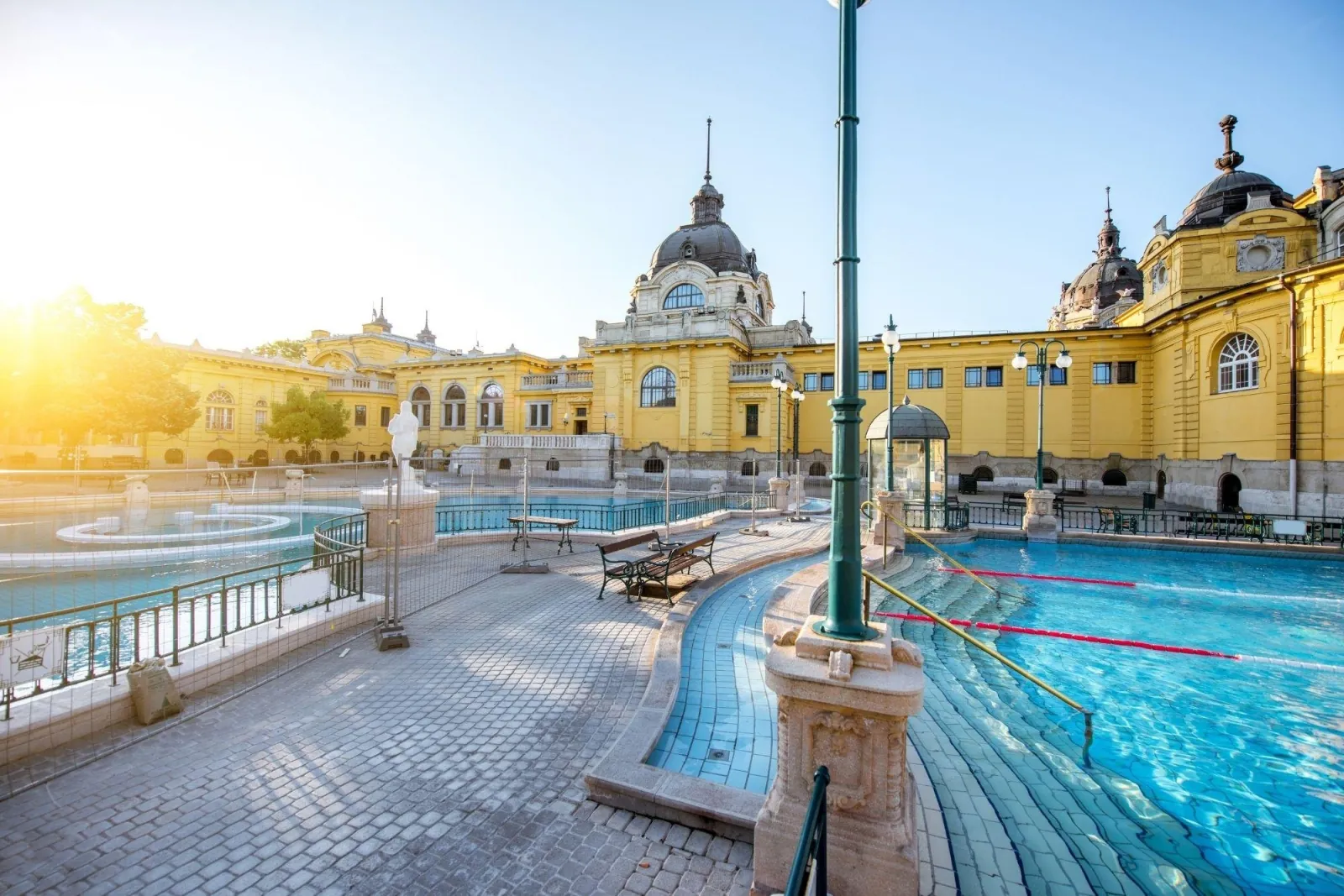 Széchenyi's outdoor swimming pool lanes and courtyard in early morning sunlight