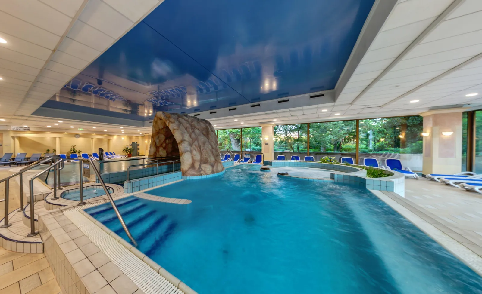Indoor thermal pool at Ensana Thermal Margaret Island, steps into the water and garden windows behind