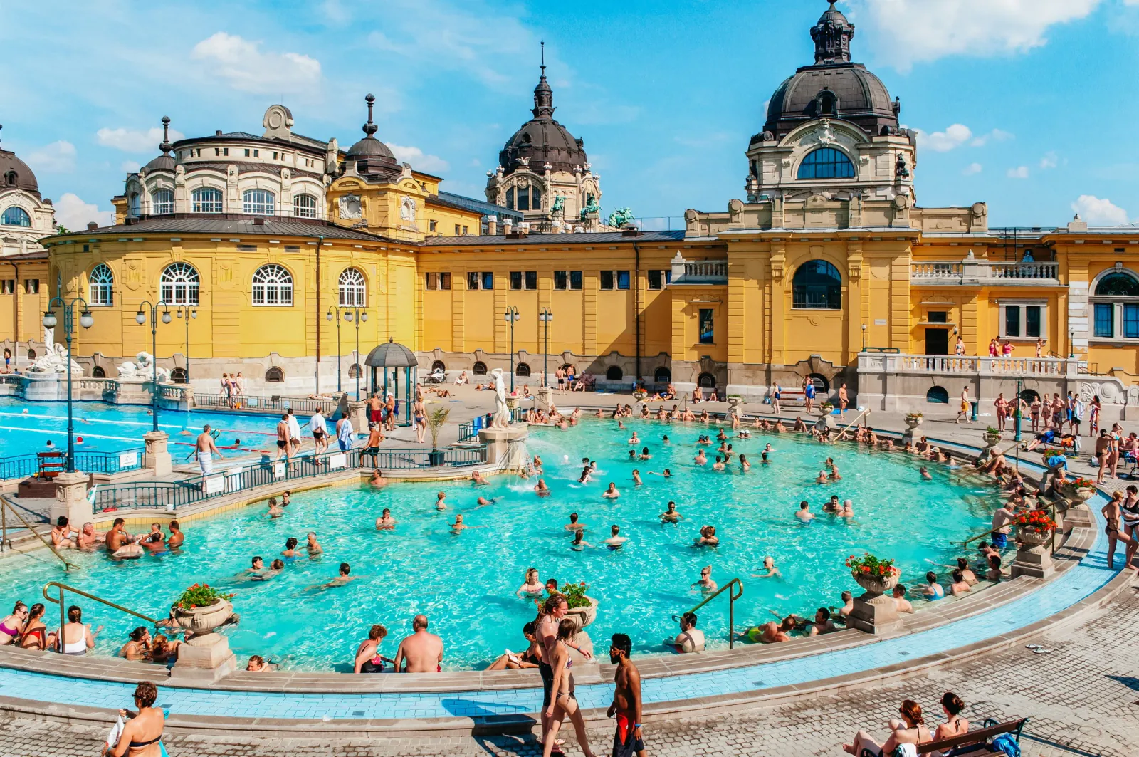 Crowded semicircular outdoor thermal pool at Széchenyi on a sunny summer day