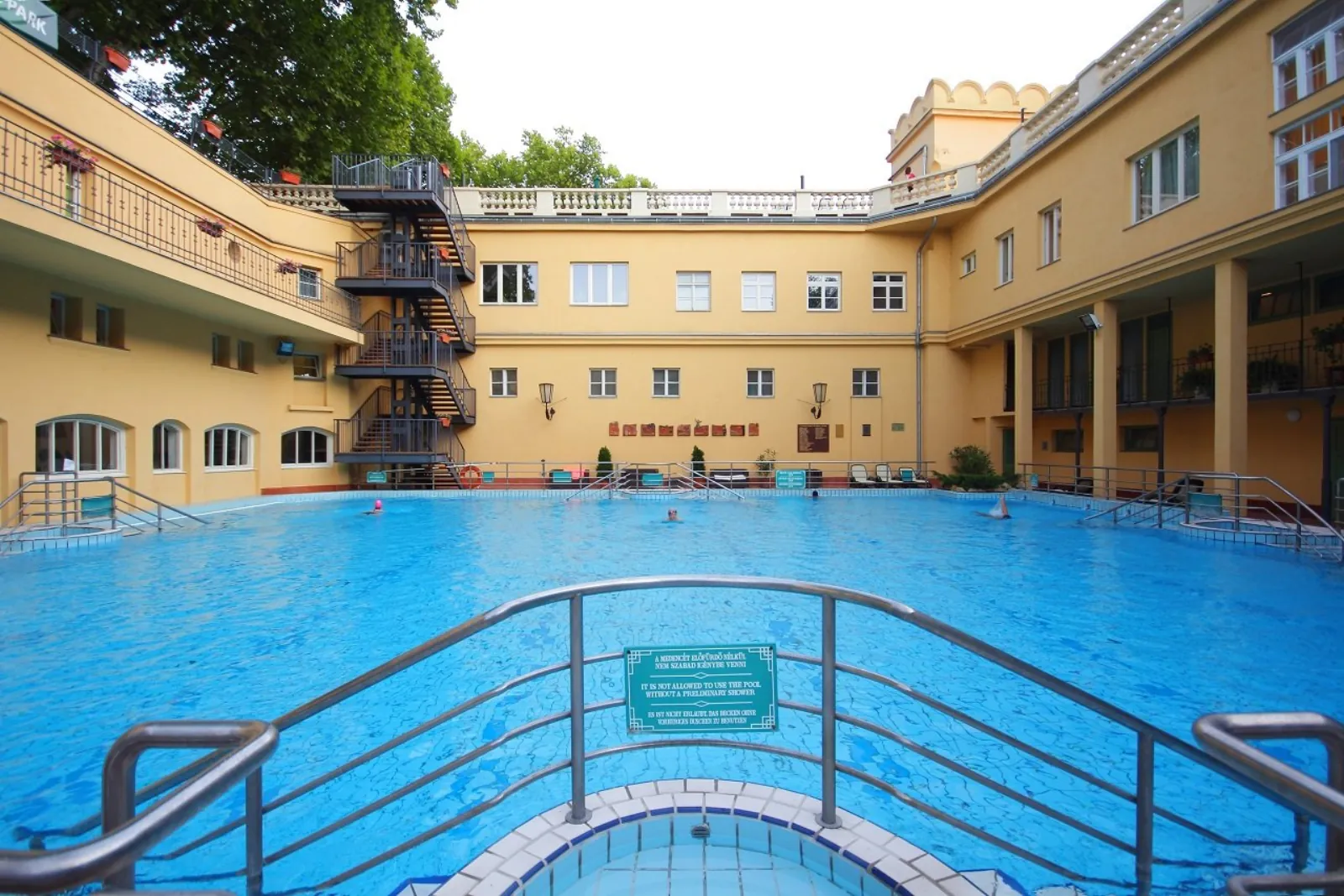 Lukács outdoor swimming pool in the yellow courtyard with an iron spiral staircase